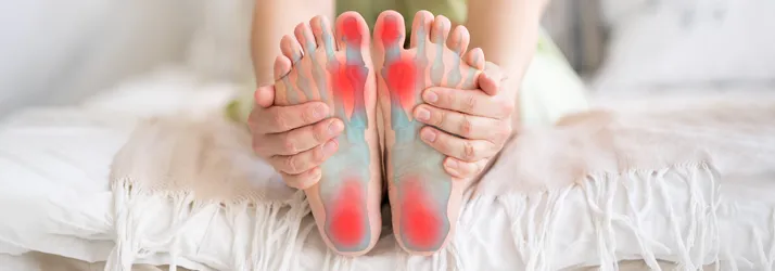 A person holding their feet. Their feet are highlighted red.